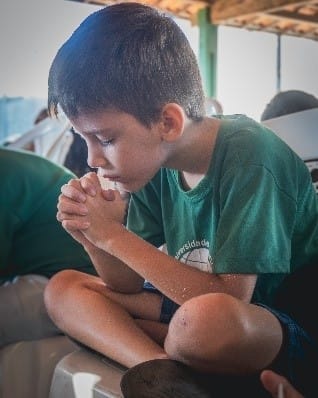 Young boy in prayer at Univida