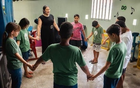 Children standing, holding hands in a circle.